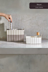 Beyaz ve bej renkte plastik saklama kutuları, kitap ve cam şişe ile, gri duvar önünde