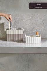 Beyaz ve bej renkte plastik saklama kutuları, kitap ve cam şişe ile, gri duvar önünde