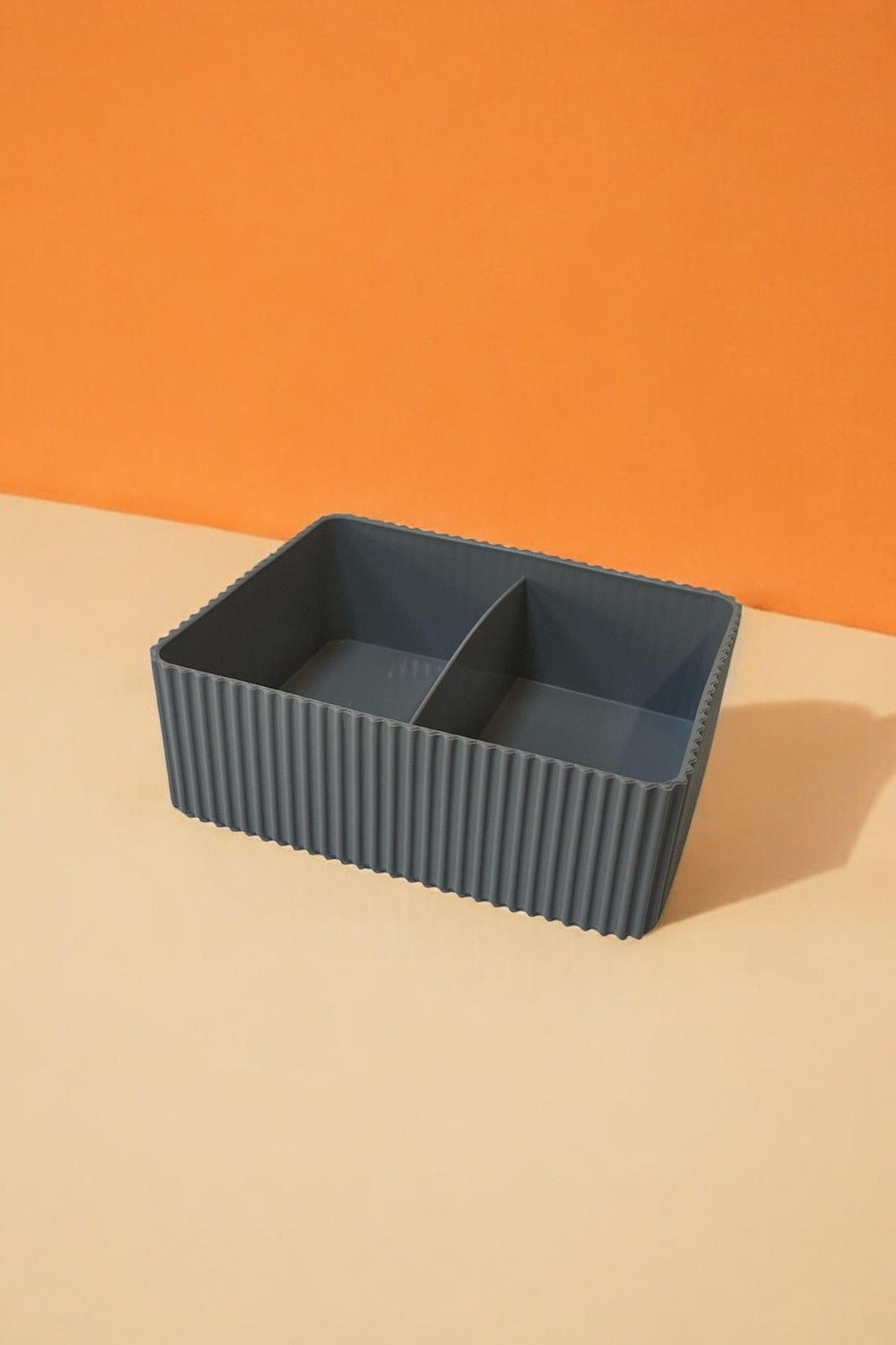 İki bölmeli gri dalgalı plastik saklama kutusu üzerinde turuncu ve bej zemin
