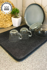 Kahverengi havlu üstünde ters çevrilmiş şeffaf cam kupalar ve tabaklar, mutfak tezgahında