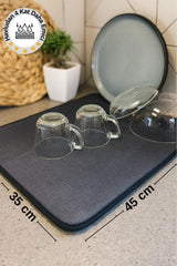 45x35 cm ölçülerinde gri emici mutfak havlusu, cam bardaklar ve tabaklarla mutfak tezgahında