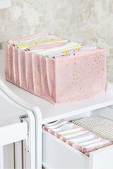 Pembe yıldız desenli kumaş düzenleyicide katlanmış bebek kıyafetleri ve çekmece içi düzenleme