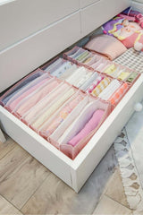 Çekmecede düzenli katlanmış renkli ev tekstili ve pembe organizatör kutuları