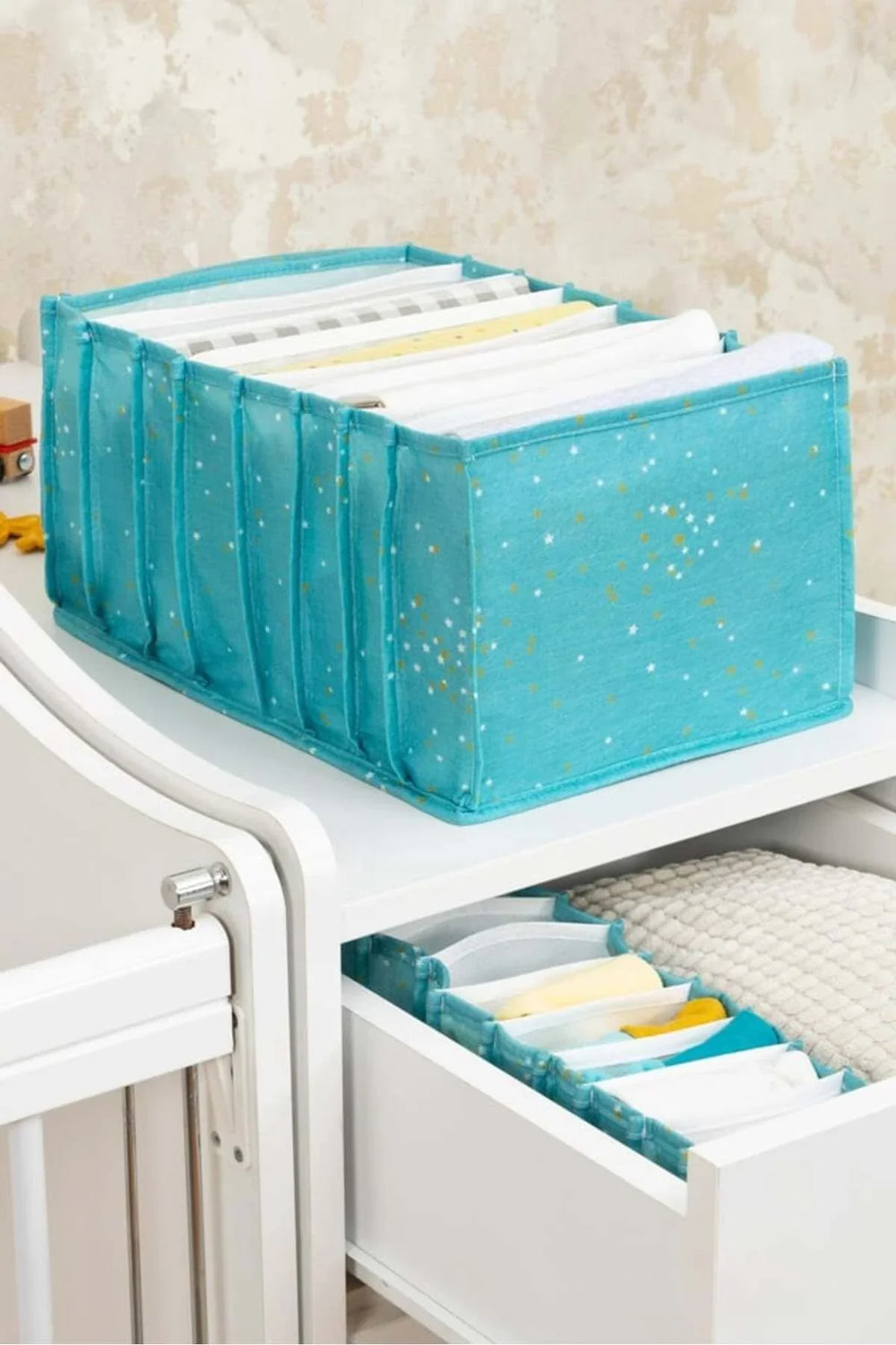 Mavi yıldız desenli kumaş organizer kutu ve çekmecede düzenli bebek kıyafetleri