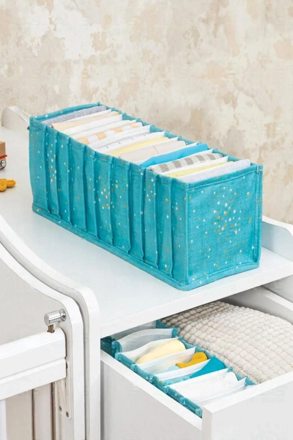 Mavi yıldız desenli bebek bezi ve kıyafet organizerı, beyaz raf ve çekmecede düzenli
