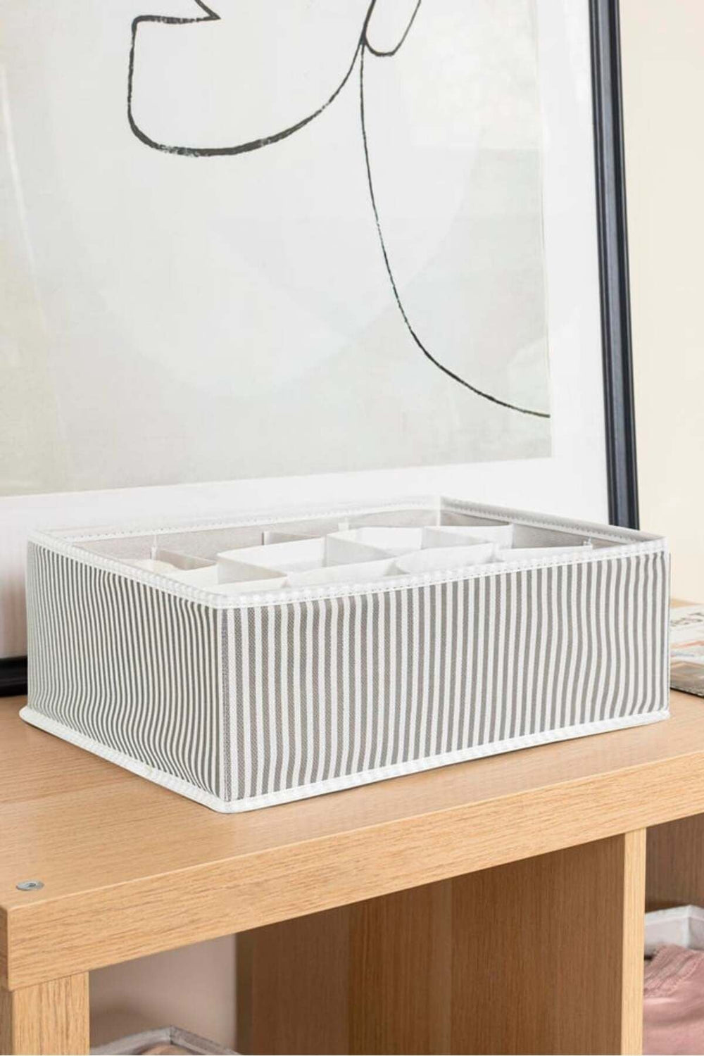 Şeffaf kapaklı, çizgili gri-beyaz kumaş kutu ve bölmelerle ahşap masa üzerinde düzenleyici