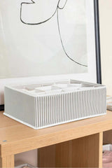 Şeffaf kapaklı, çizgili gri-beyaz kumaş kutu ve bölmelerle ahşap masa üzerinde düzenleyici