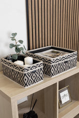 Doğal ahşap raf üzerinde siyah-beyaz geometrik desenli iki dekoratif saklama kutusu