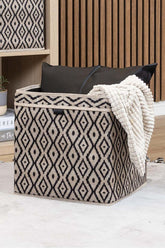 Siyah desenli kumaş saklama kutusunda siyah yastık ve krem dokulu battaniye