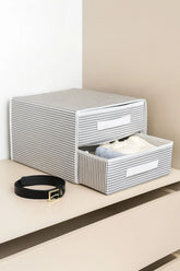 Gri beyaz çizgili kumaş çekmeceli düzenleyici ve bej dolap üzerinde siyah deri kemer