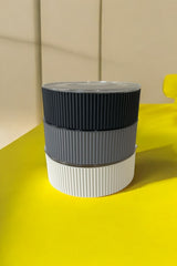 Üst üste dizilmiş siyah, gri ve beyaz renkli yuvarlak plastik saklama kapları