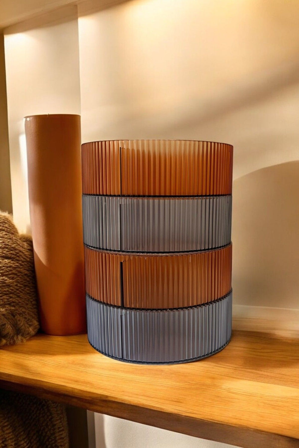 Ahşap rafta turuncu ve gri renkli, çizgili modern dekoratif lamba ve kahverengi silindir obje