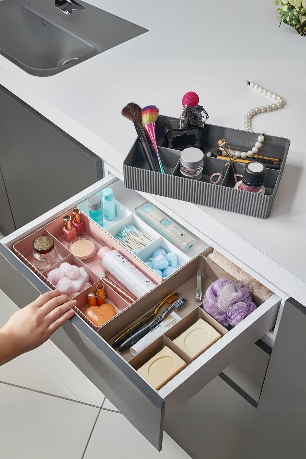 Beyaz çekmecede makyaj fırçası, parfüm, makyaj malzemeleri ve kişisel bakım ürünleri düzenleyici kutular