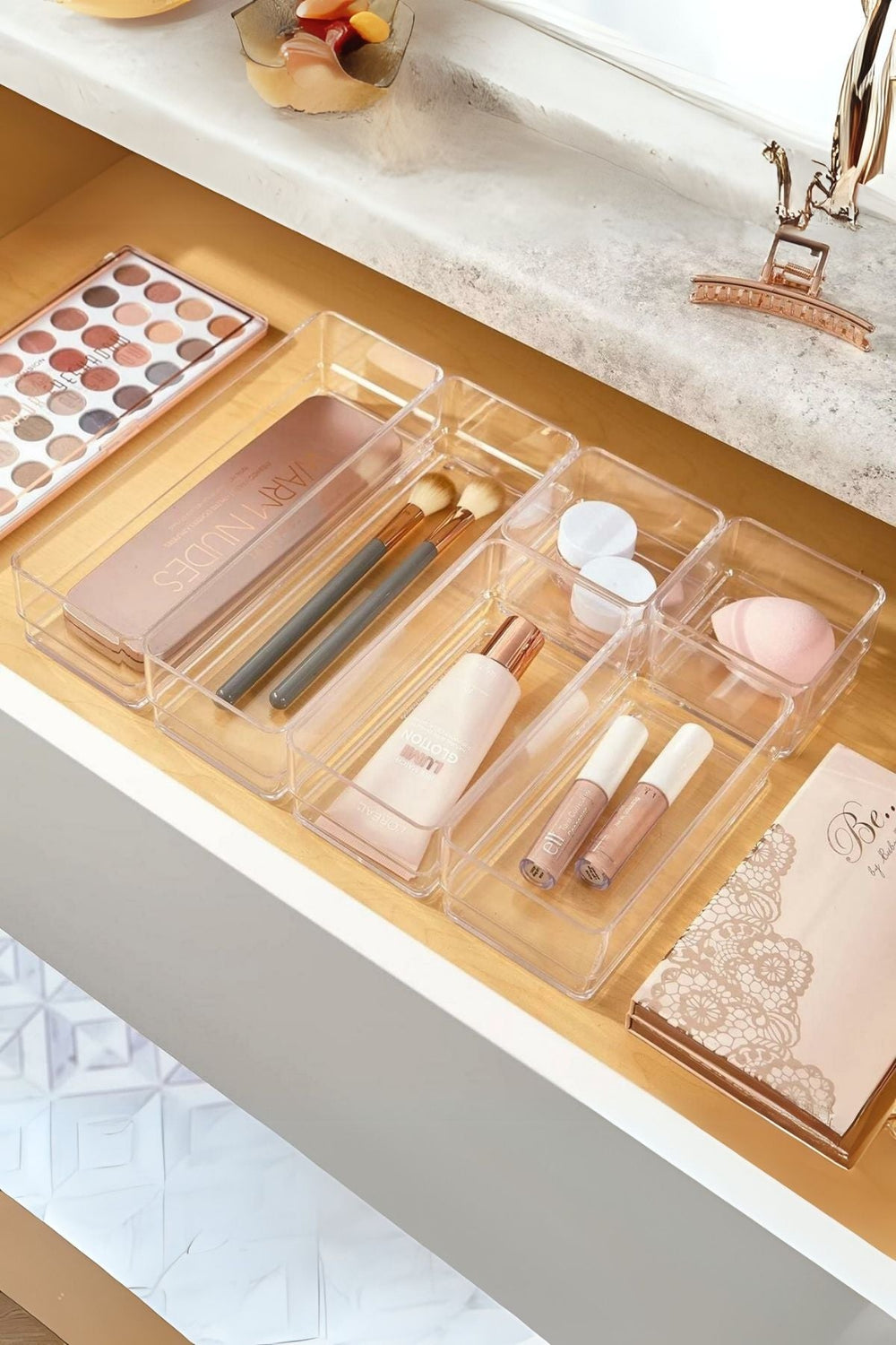 Açık ahşap çekmecede şeffaf makyaj organizatörü, fırçalar, fondöten, allık paleti ve makyaj süngeri