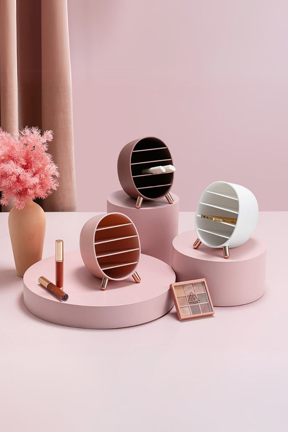 Pastel pembe arka planda yuvarlak raflarda dekoratif mini yuvarlak raflar ve makyaj ürünleri