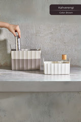 Gri duvar önünde kahverengi ve beyaz plastik kutular, biri kitap diğeri cam şişe ile