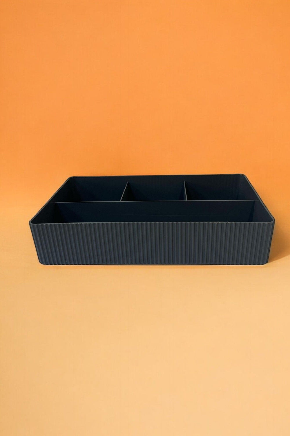Bölmeli siyah plastik organizer kutu turuncu arka planda