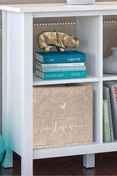 Beyaz kitaplıkta altın burunlu gergedan figürü ve mavi kitaplar üzerine yerleştirilmiş