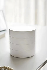 Minimalist beyaz yuvarlak kutu, modern masa üstünde, soft ışık ve dekoratif inci kolye