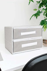 Beyaz masa üzerinde çizgili iki çekmeceli gri beyaz saklama kutusu