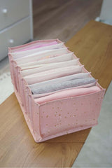 Yatak odasında ahşap masada pembe yıldıztıraşlı kumaş iç çamaşırı düzenleyici kutu