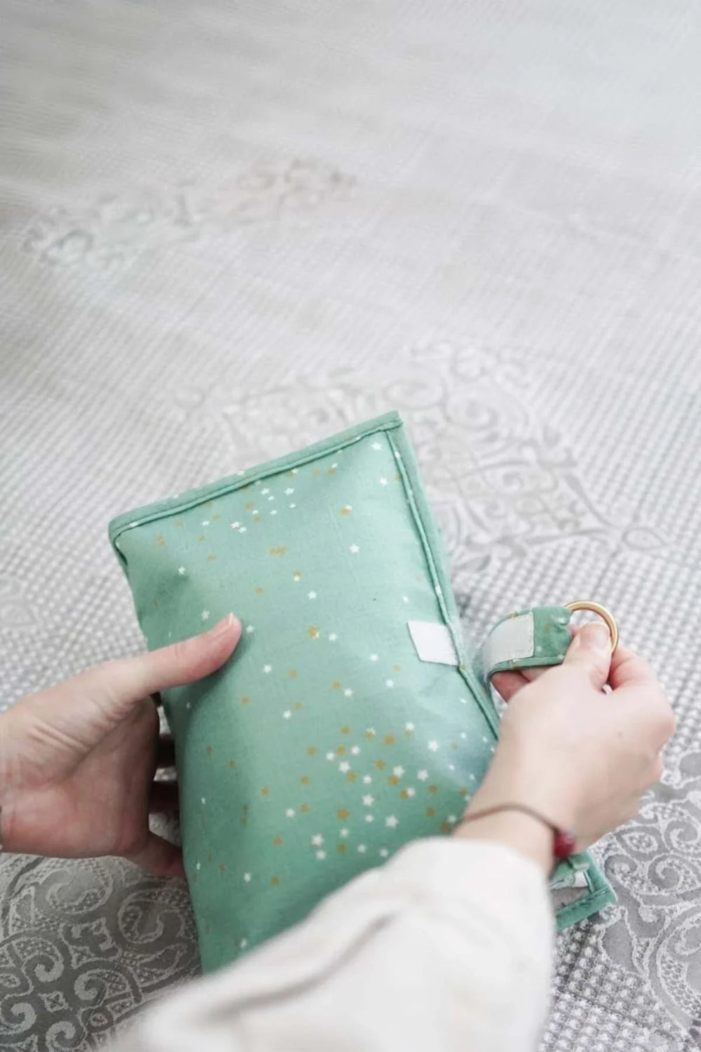 Yıldız desenli yeşil aromaterapi yastığını tutan eller, dekoratif gri zemin üzerinde