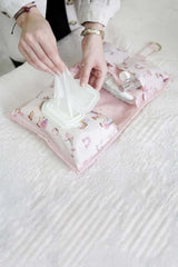 Pembe desenli bebek bakım çantasında ıslak mendil çıkartılan eller ve bebek ürünleri