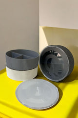 Gri ve beyaz renkli bölmeli plastik saklama kutuları, şeffaf kapaklı, sarı yüzeyde