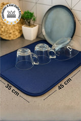 Mavi bulaşık kurutma matı üzerinde cam bardaklar ve tabak, mutfak tezgahında