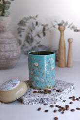 Çiçek desenli mavi kapaklı kahve kutusu ve seramik tabakta kahve çekirdekleri