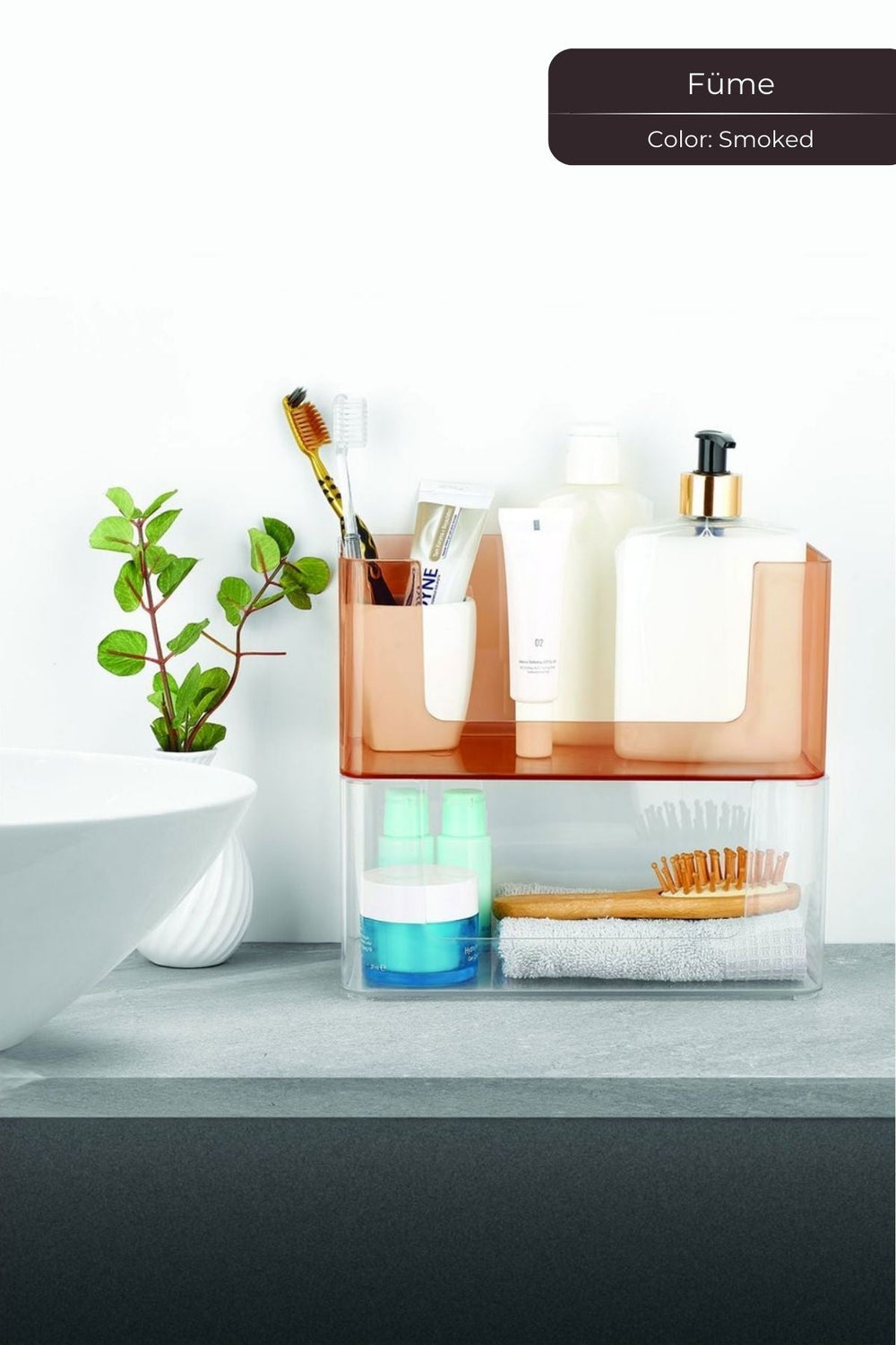 Banyo tezgahında fume renkli şeffaf plastik düzenleyicide diş fırçası, diş macunu, saç fırçası ve kozmetik ürünler