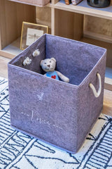 Mavi tüylü saklama kutusunda oyuncak ayı bulunan çocuk odası ortamı