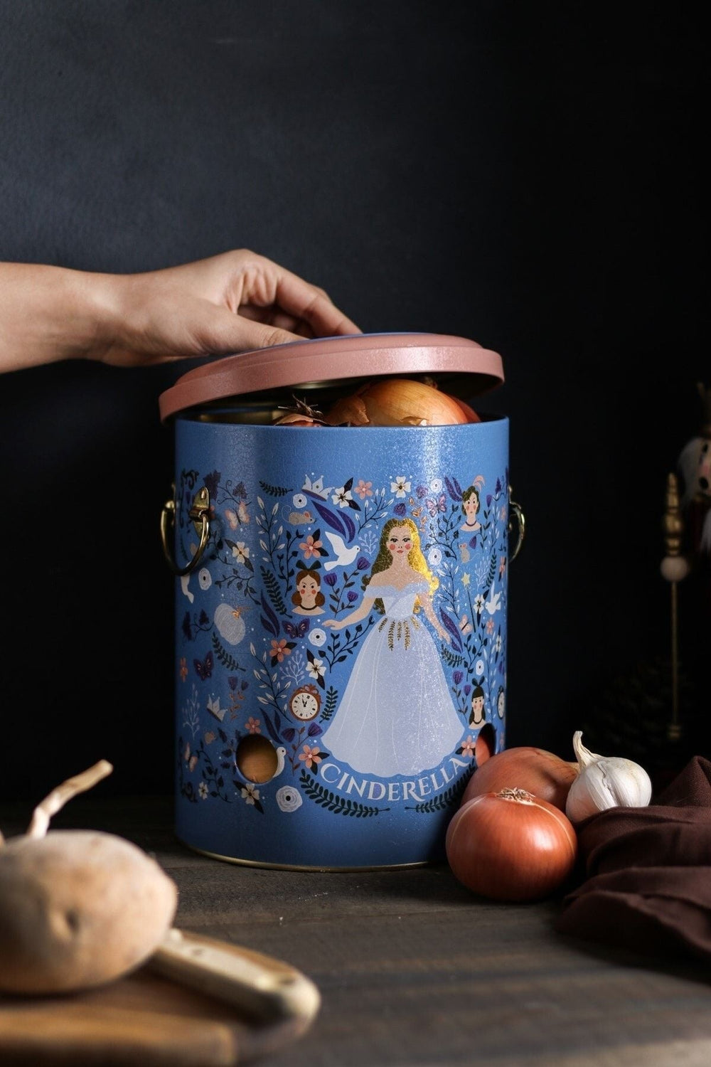Mavi külah kapaklı Cinderella desenli soğan ve sarımsak saklama kutusu, yanında soğan ve sarımsaklar