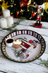 Yılbaşı dekorlu tepsi içinde kahve fincanı ve yaprak şeklinde kurabiye, arka planda noel asker süsü ve mumlar