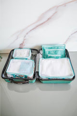 Mavi seyahat seti içinde düzenli bebek kıyafetleri ve organizer çantalarla açık valiz