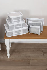 Beyaz çizgili gri bavul organizer seti, beyaz masada ve ahşap zemin üzerinde