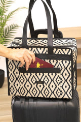 Elin pasaport koyduğu siyah beyaz desenli çok amaçlı bohem seyahat çantası, siyah valizin üzerinde