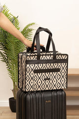 El tutmalı siyah beyaz geometrik desenli çok amaçlı seyahat çantası, siyah sert valizin üstünde