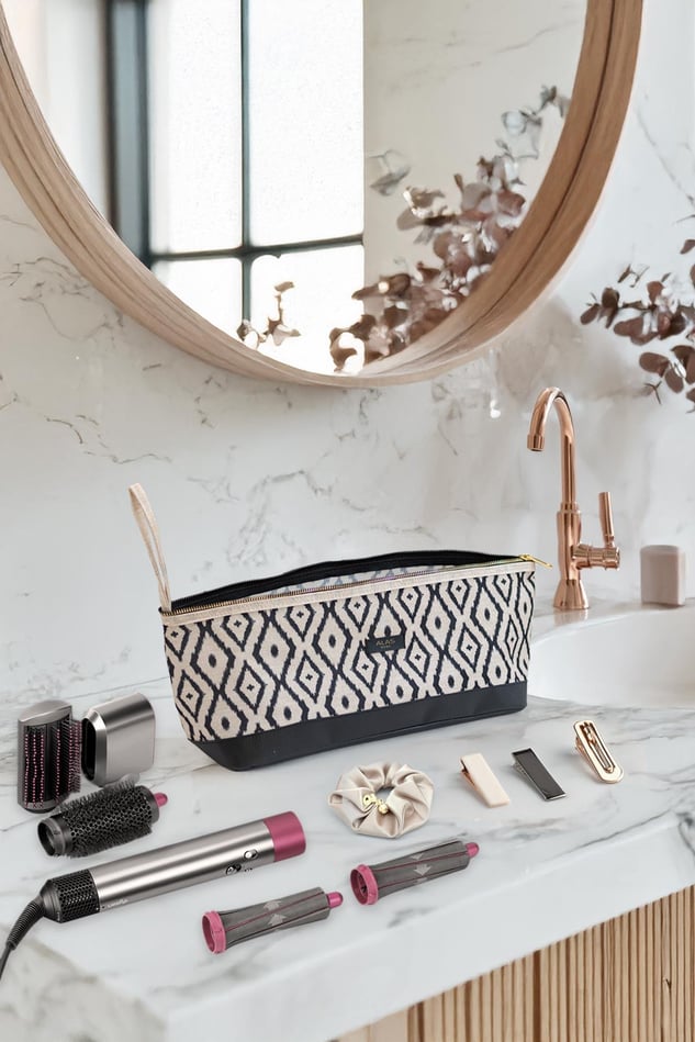 Desenli bohem saç şekillendirici çanta, saç maşası, fırçalar ve aksesuarlar beyaz mermer tezgah üzerinde