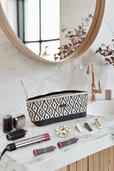 Desenli bohem saç şekillendirici çanta, saç maşası, fırçalar ve aksesuarlar beyaz mermer tezgah üzerinde