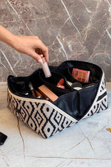 Desenli siyah beyaz bohem makyaj çantası ve el ile alınan likit makyaj ürünü