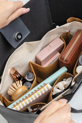 Çanta organizatöründe saç fırçası, cüzdan, defter ve kozmetik ürünleri düzenli şekilde