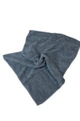 Koyu gri mikrofiber havlu, yumuşak dokulu ve büzülmüş şekilde beyaz zeminde