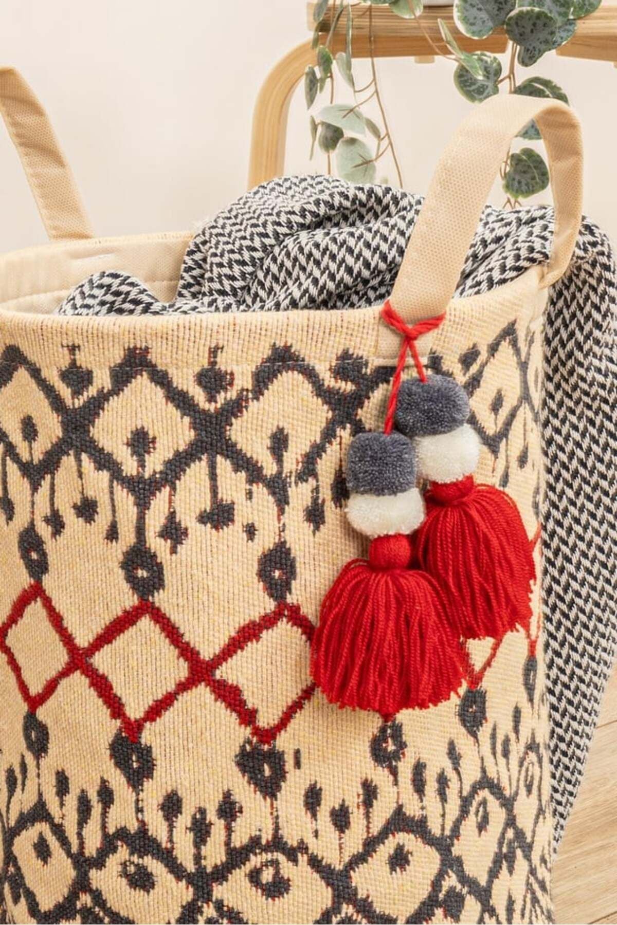 Kırmızı ve siyah desenli dekoratif hasır sepet içinde siyah beyaz battaniye ve kırmızı püsküller