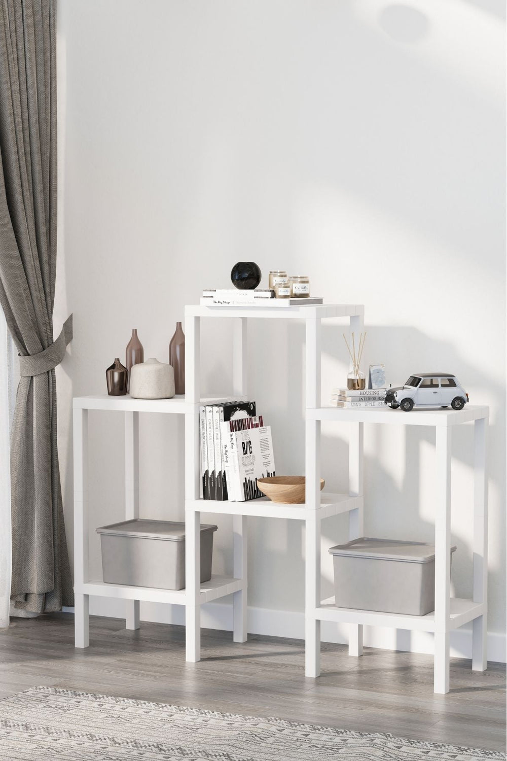 Beyaz modüler ev kitaplığı, kitaplar, dekoratif vazolar, mumlar ve minyatür arabanın yer aldığı modern oturma odası