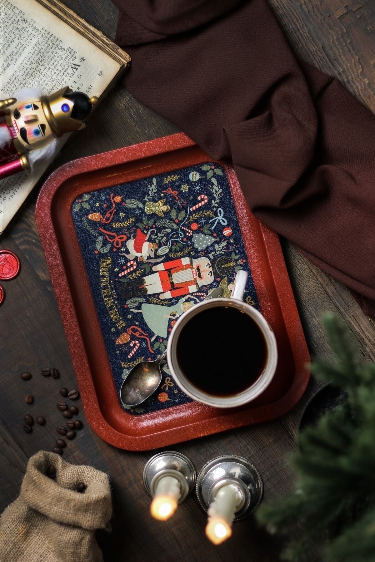 Kahverengi bez, kitap ve kukla ile Noel temalı tepsi üzerinde kahve ve ışıklı mumlar