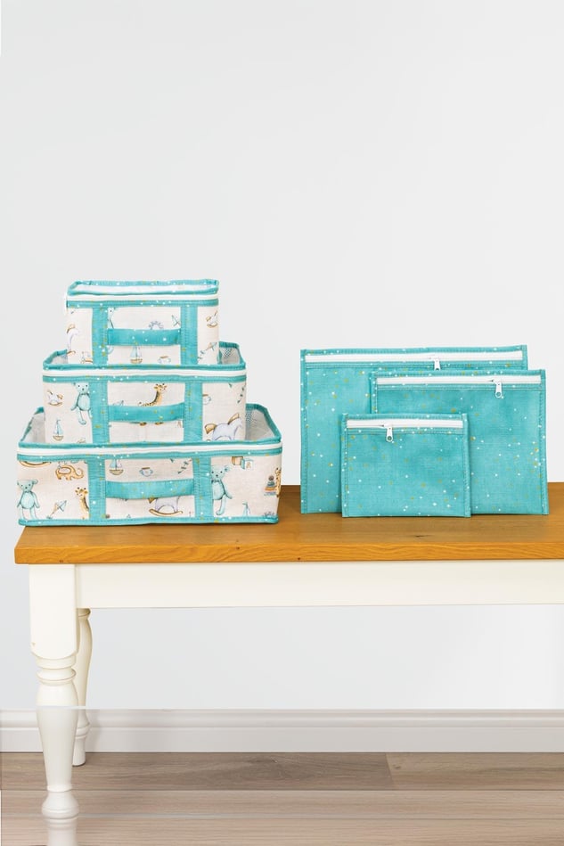 Mavi renkli bebek desenli düzenleyici kutular ve mavi fermuarlı saklama çantaları masa üstünde
