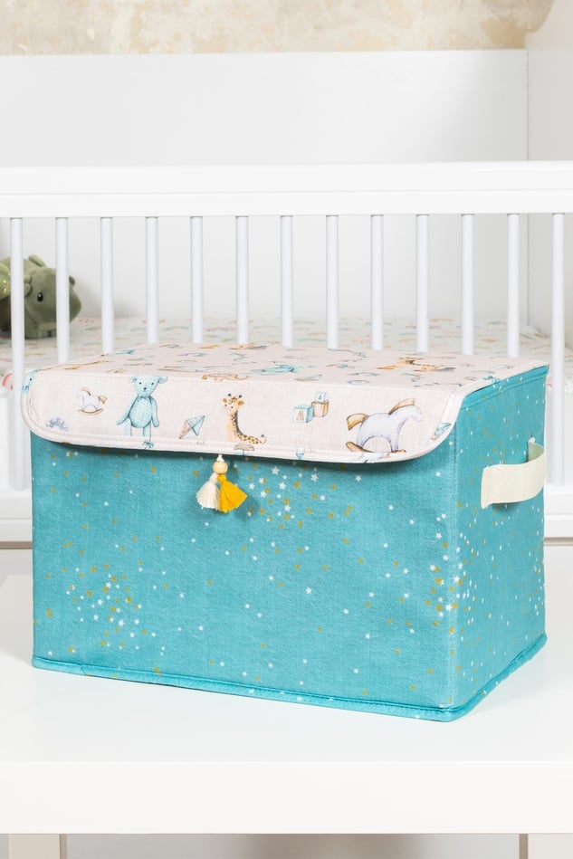 Mavi ve desenli kapaklı bebek oyuncak ve ek malzeme kutusu, beşik önünde