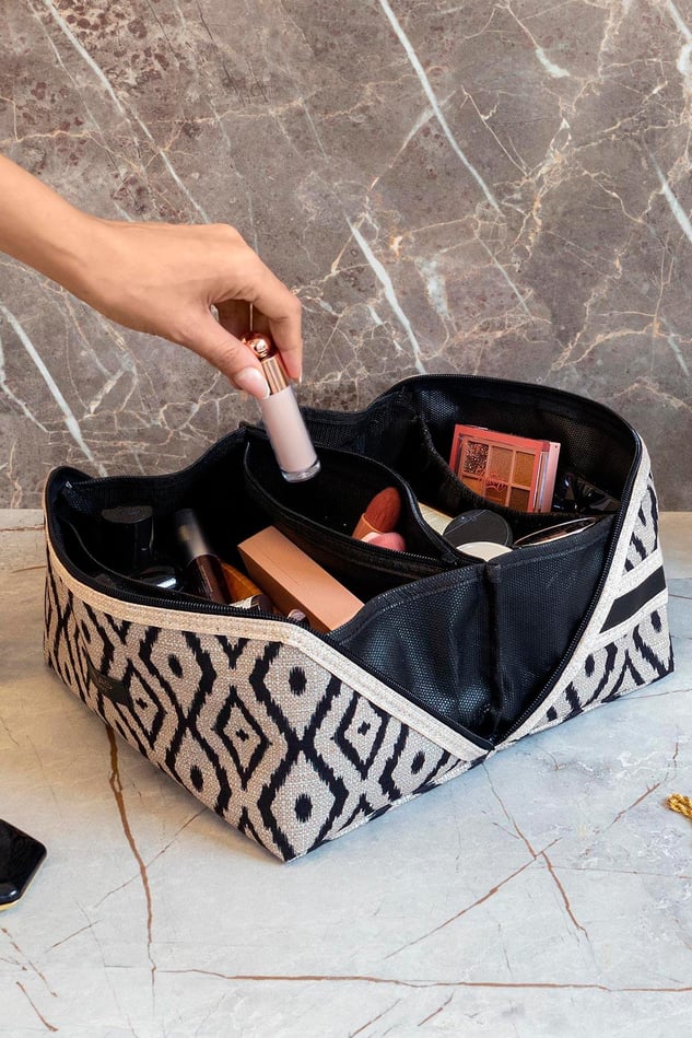 Desenli siyah beyaz bohem makyaj çantası ve el ile alınan likit makyaj ürünü